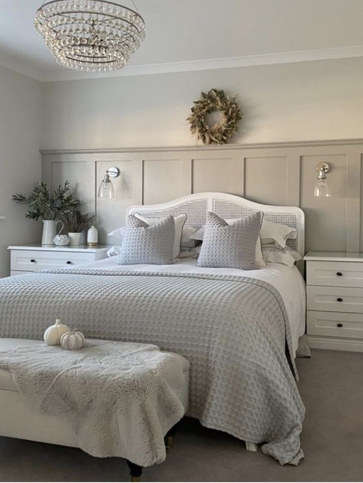 a bedroom with a bed, dressers and a chandelier