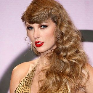 a woman with long wavy hair and red lipstick wearing a gold dress at an event