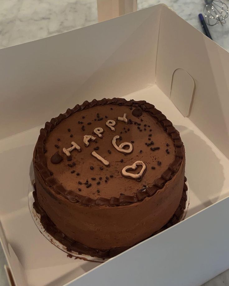 a chocolate cake in a white box with the words happy 50th on it and sprinkles