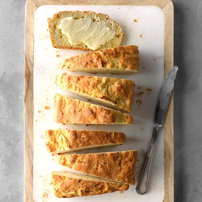 slices of bread on a cutting board with knifes and lemon wedges next to it