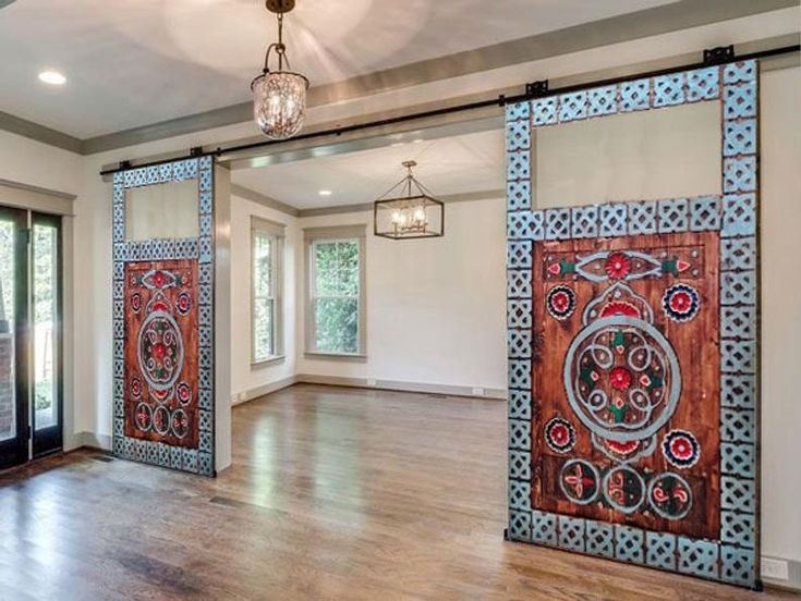 an empty living room with wooden floors and large mirrors on the wall above it's doors