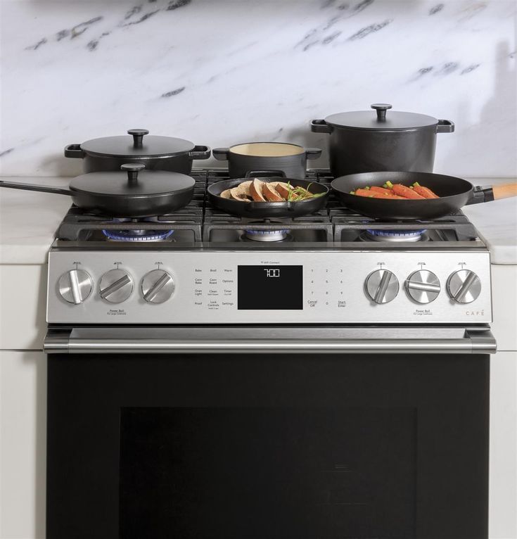 an oven with pots and pans on the burners, in front of a marble counter top