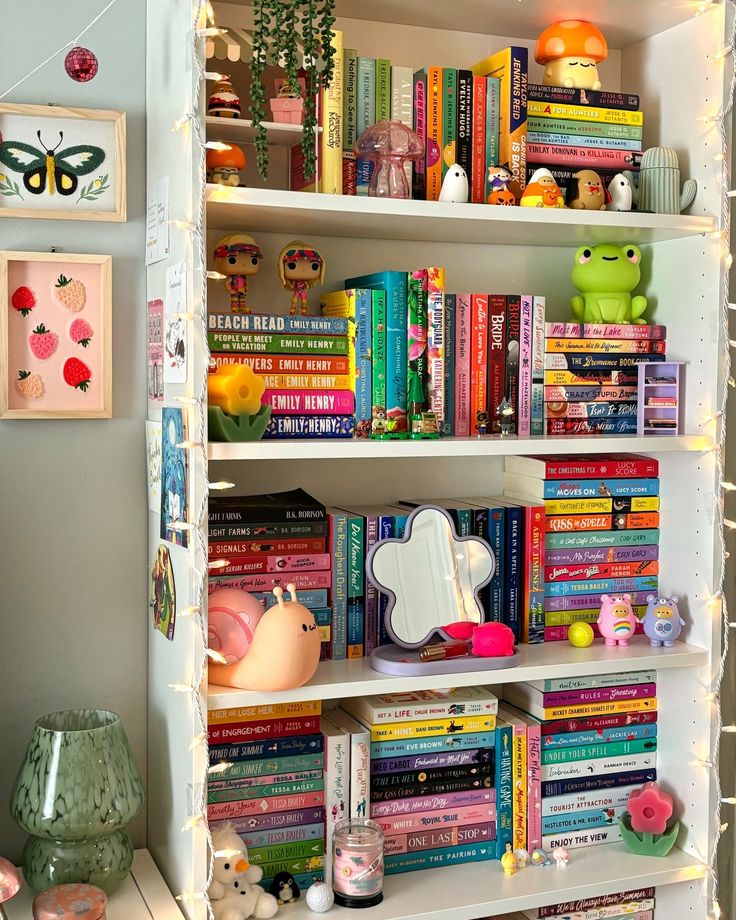 a bookshelf filled with lots of books and stuffed animals on top of it