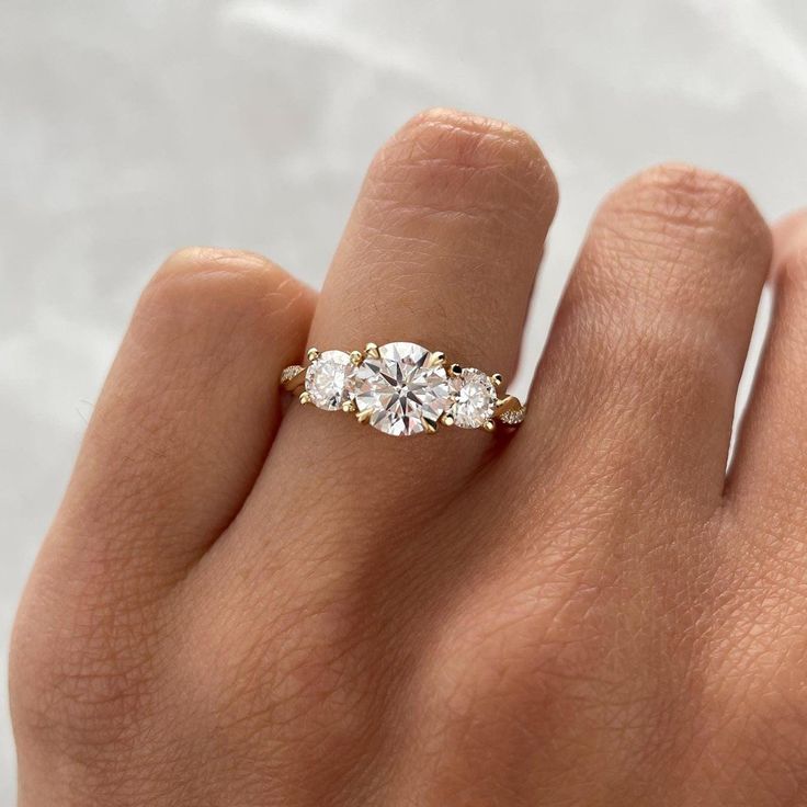 a woman's hand with a three stone ring on it