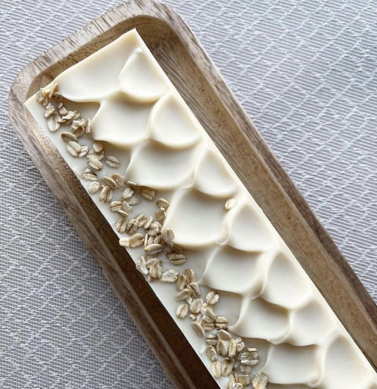 a wooden tray with white frosting on it and gold flowers in the center, sitting on a table