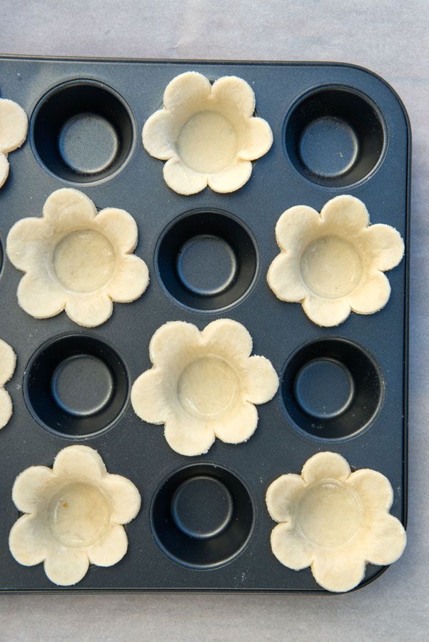 an uncooked muffin pan with flower shaped doughnut holes