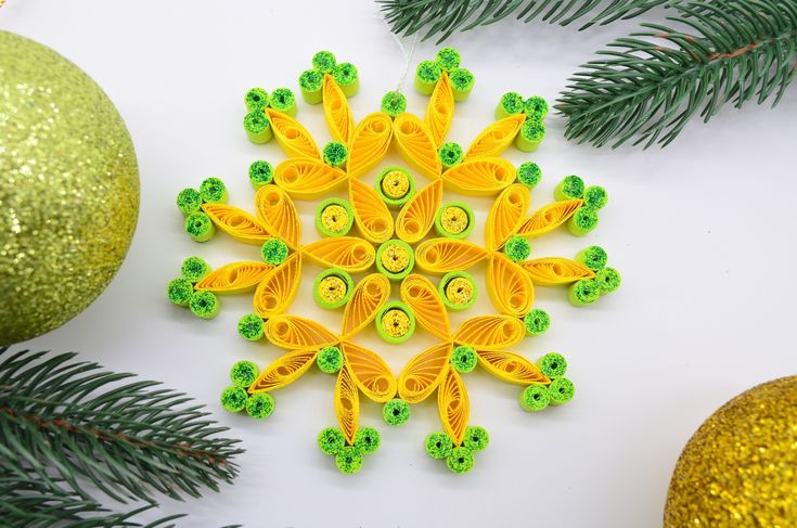 an ornament made out of yellow and green plastic beads next to christmas ornaments