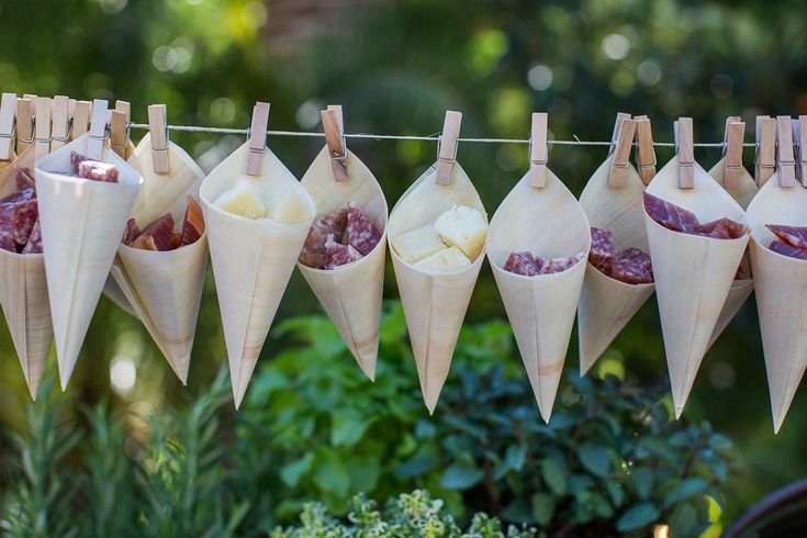 some food hanging on a clothes line in front of plants and bushes with other foods