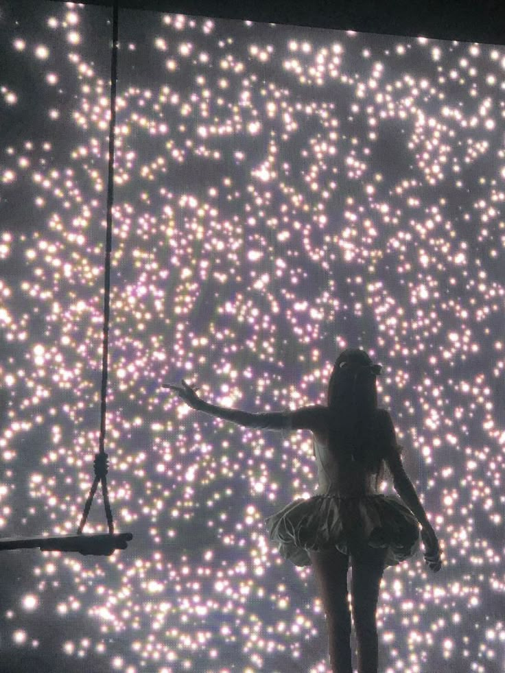 a woman standing in front of a large screen with lights on it's sides