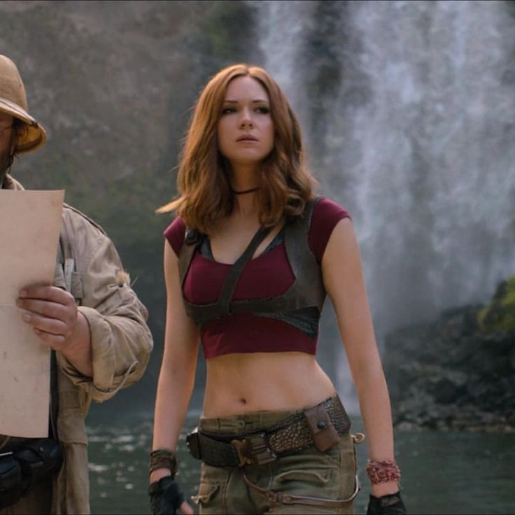 a man and woman standing next to each other in front of a waterfall holding papers