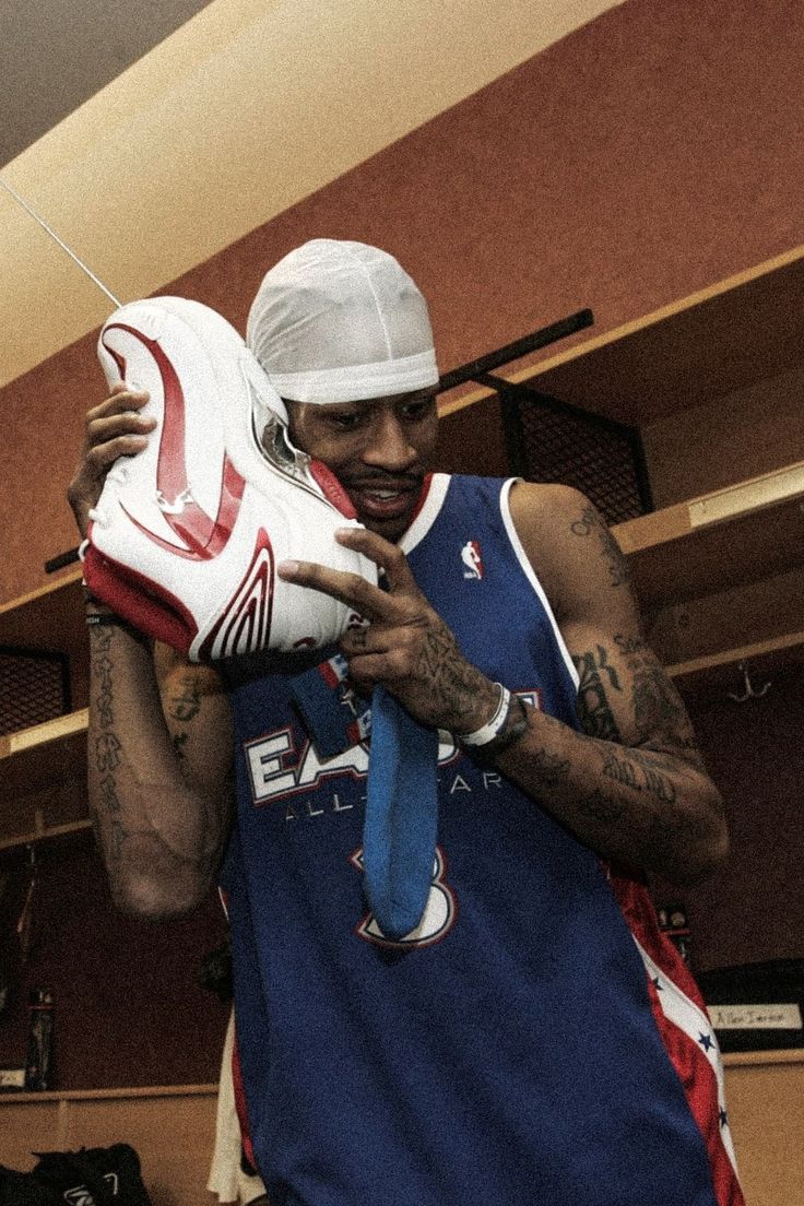 a man holding a basketball shoe in his hand and wearing a bandana around his neck