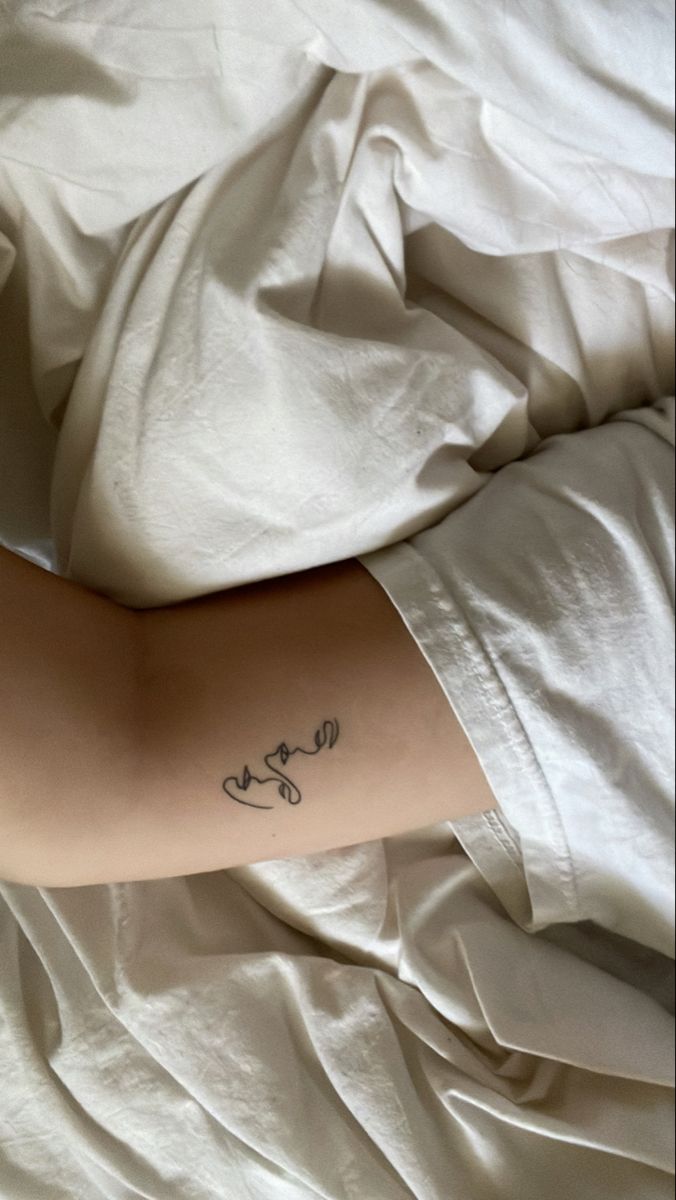 a person laying in bed with a tattoo on their arm that says love and flowers