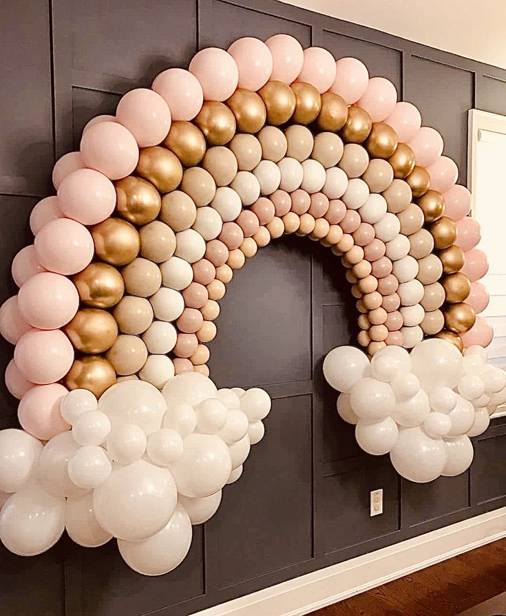 a large arch made out of balloons in the shape of a rainbow on a wall