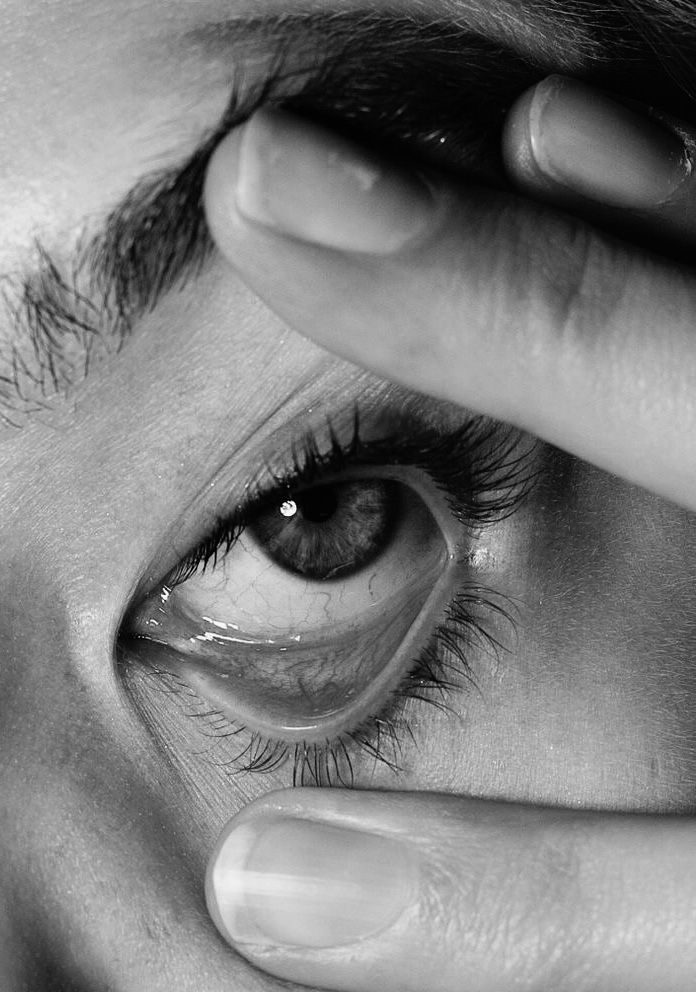 a close up of a person's eye with their hand on the iris