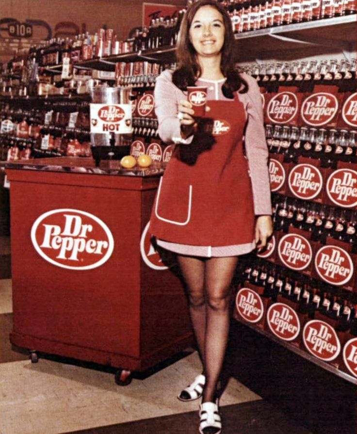 a woman standing in front of a display of dr pepper's sodas and holding a cat