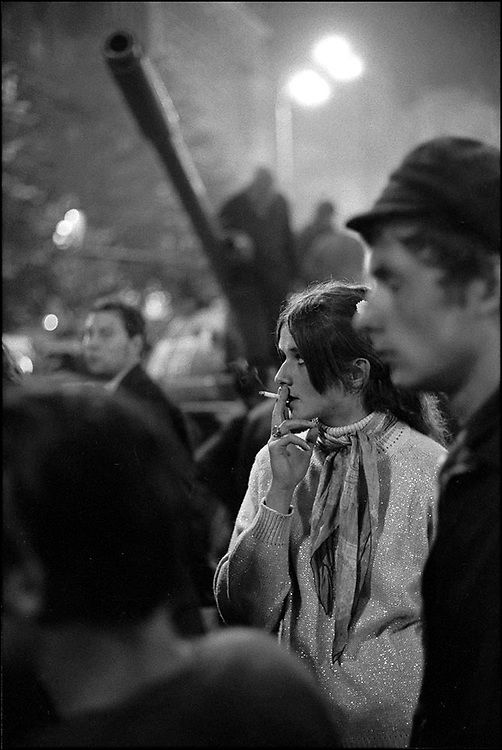 two people standing next to each other talking on their cell phones in front of a crowd