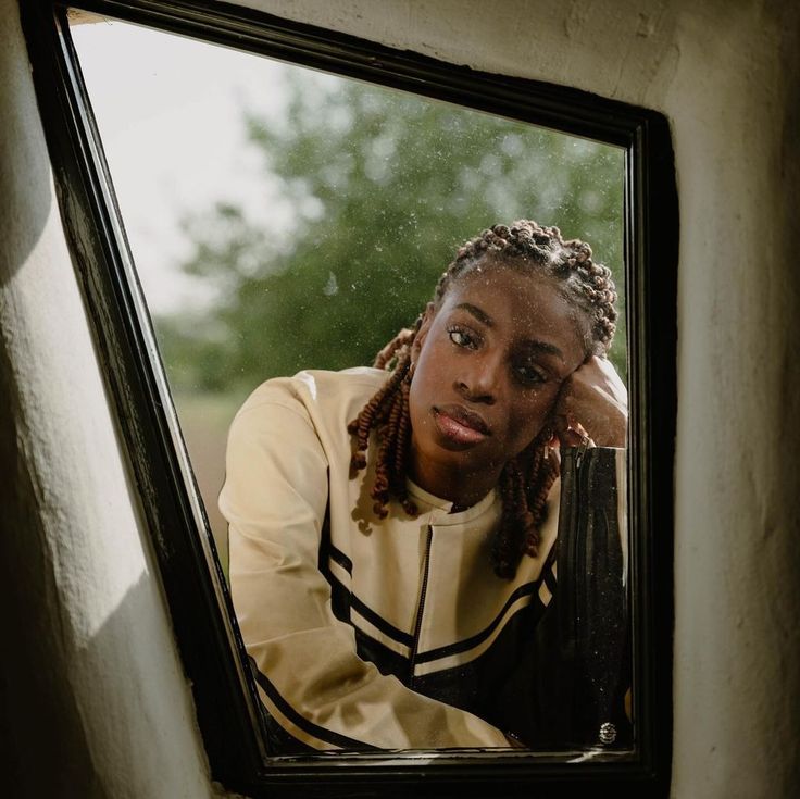 a woman with dreadlocks looking into a mirror