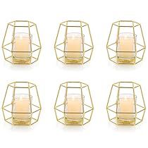 six gold metal candle holders with candles in them