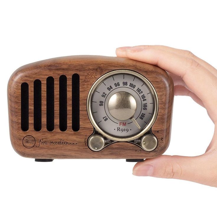 a hand holding an old fashioned radio in it's right hand, with the dial on