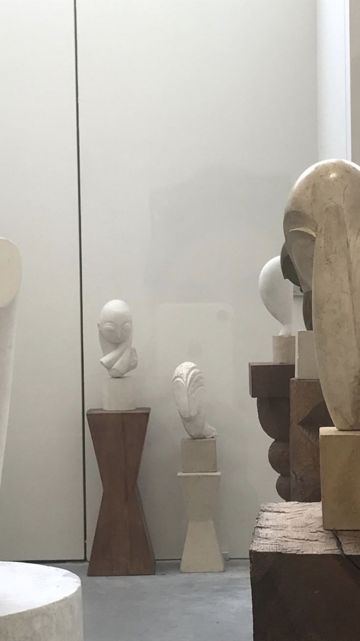 several sculptures are on display in a room with white walls and concrete flooring,