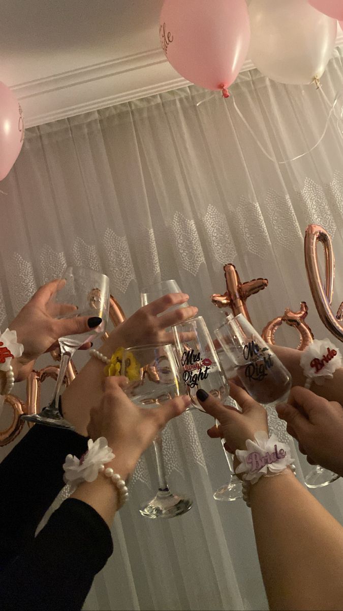 several people toasting with wine glasses in front of balloons