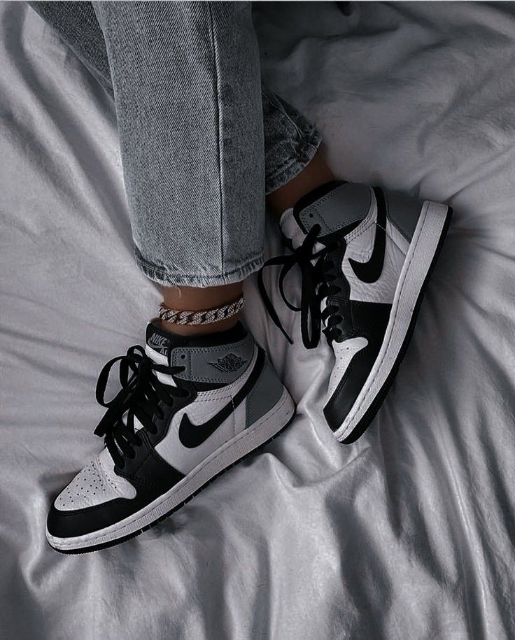 black and white photo of someone's feet wearing nike air jordans on a bed