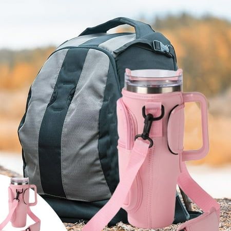 a pink and grey backpack with two water bottles on the ground next to it's side