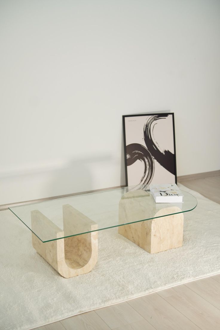 a glass coffee table sitting on top of a white rug next to a framed photograph