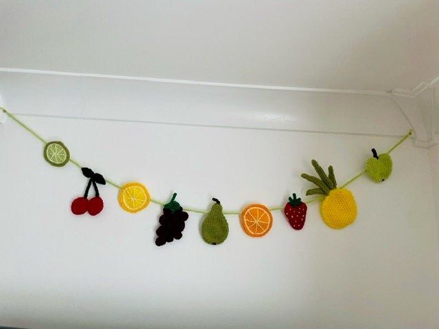 there are fruits and vegetables hanging on the line with fruit cut out to make garlands