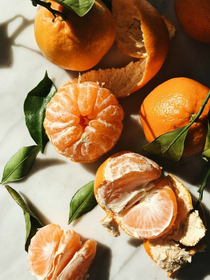 oranges with leaves and peeled ones on a table