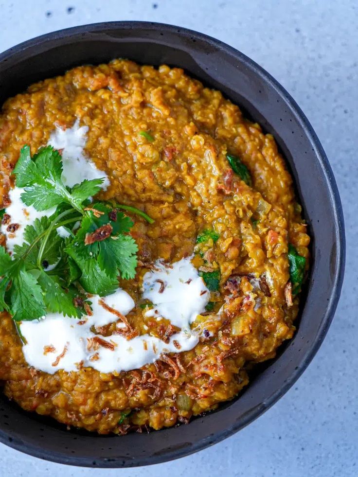 a black bowl filled with food and garnished with cilantro, sour cream and parsley