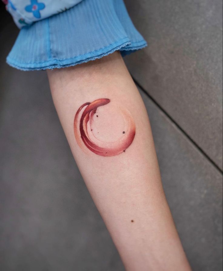 a woman's arm with a red circle tattoo on it