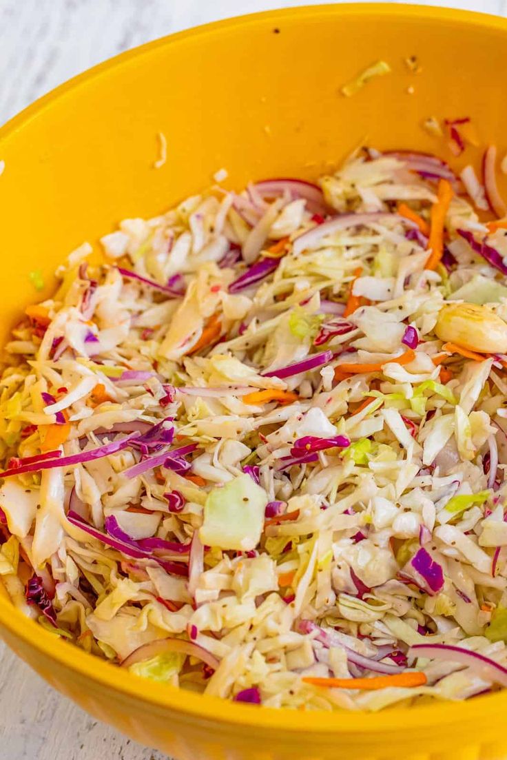 a yellow bowl filled with coleslaw and carrots