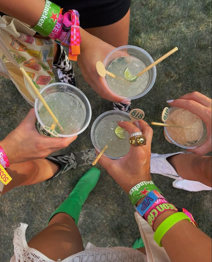 four people are holding drinks with toothpicks in their hands and wearing bracelets