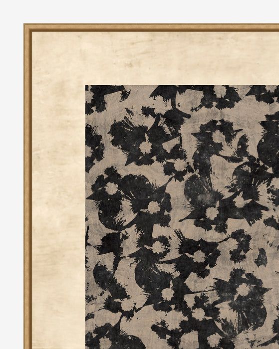 a black and white floral print in a gold frame on a beige background with an aged wooden border