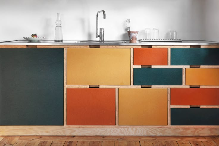 a kitchen with an island made out of multicolored wood panels and metal faucets