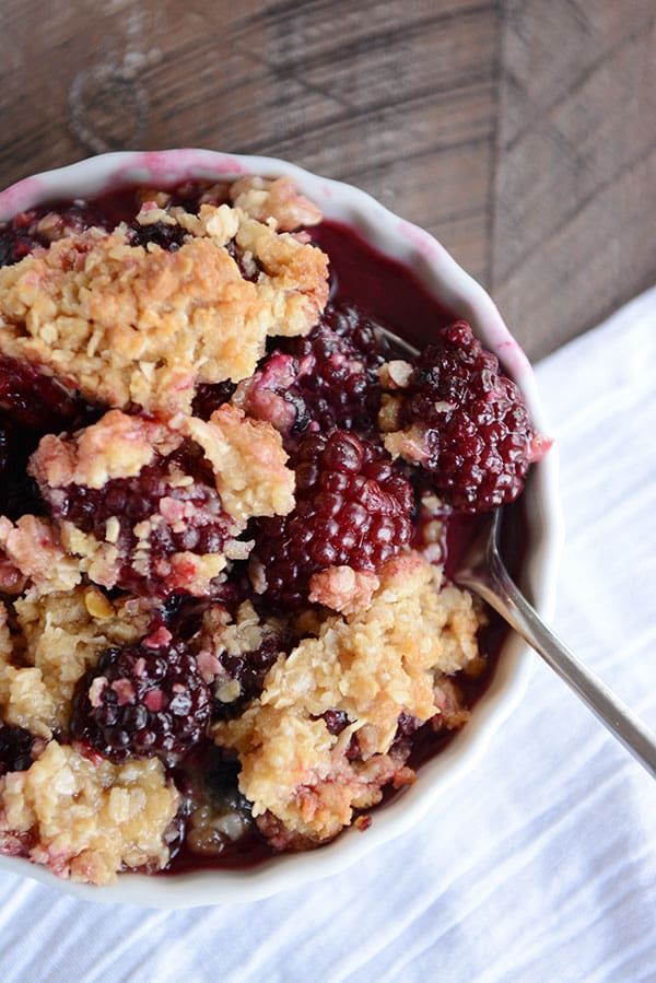 a bowl filled with crumbs and fruit on top of a white table cloth