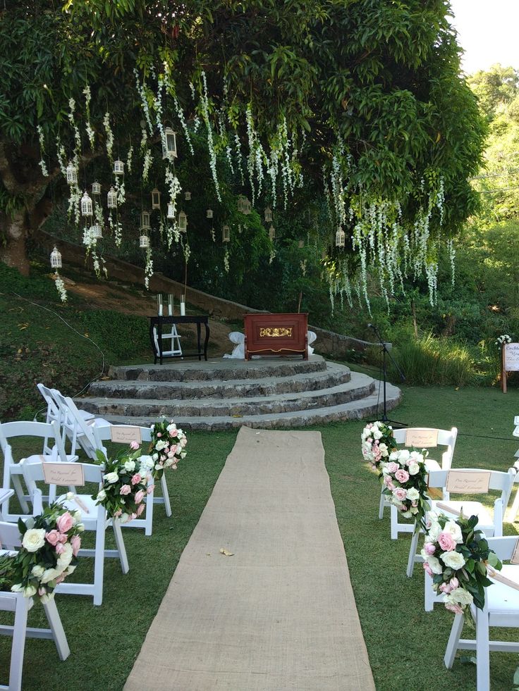 an outdoor ceremony set up with white chairs and flowers