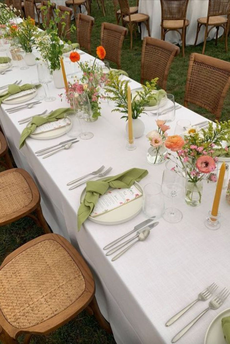 a long table with place settings and flowers on it