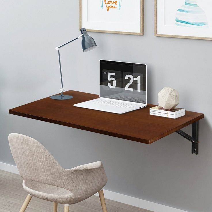 a laptop computer sitting on top of a wooden desk next to a lamp and chair