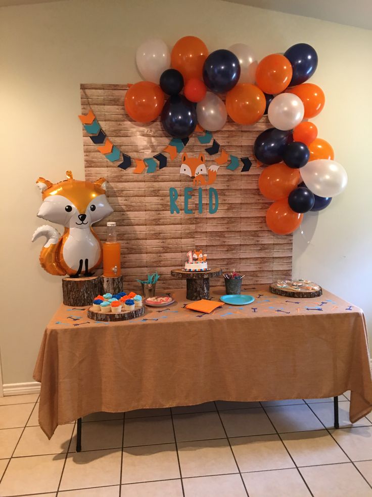 a table topped with balloons and cake next to a wooden sign that says red on it