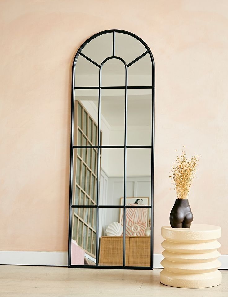 a mirror sitting on top of a table next to a vase