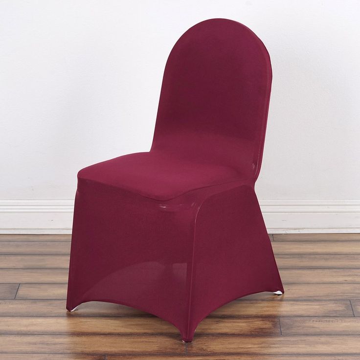 a red chair sitting on top of a hard wood floor next to a white wall