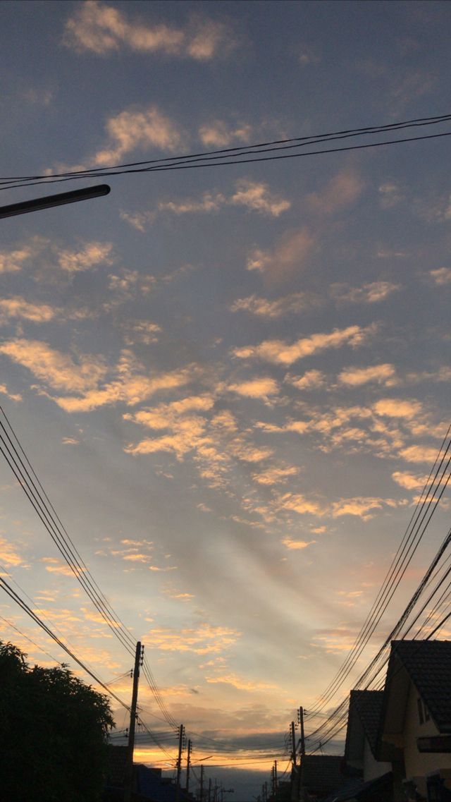 the sun is setting behind power lines and telephone poles in an urban area with houses