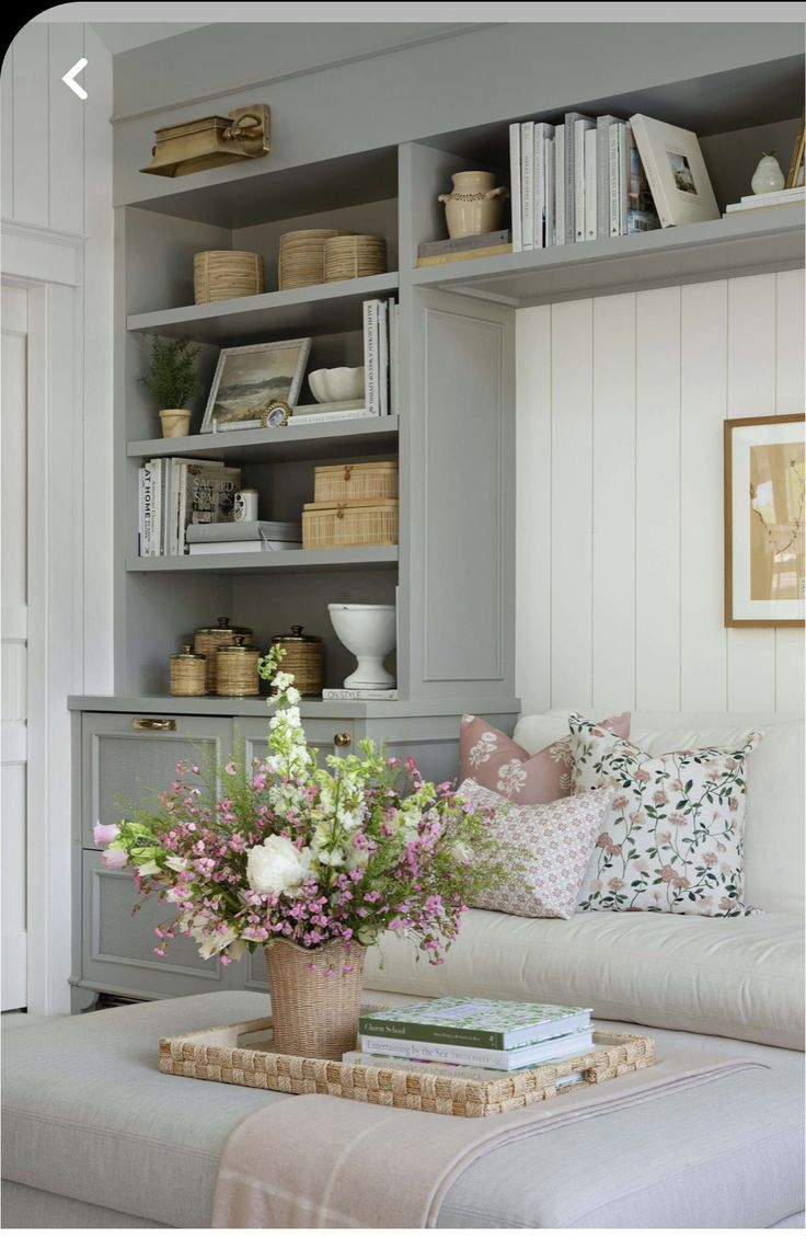 a living room filled with lots of furniture and flowers on top of a coffee table