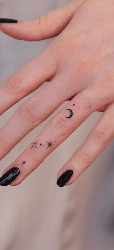 a woman's hand with stars and moon tattoos on it, while the fingers are black