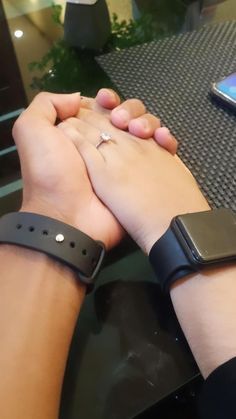 two people holding hands while sitting at a table with their cell phones on top of them