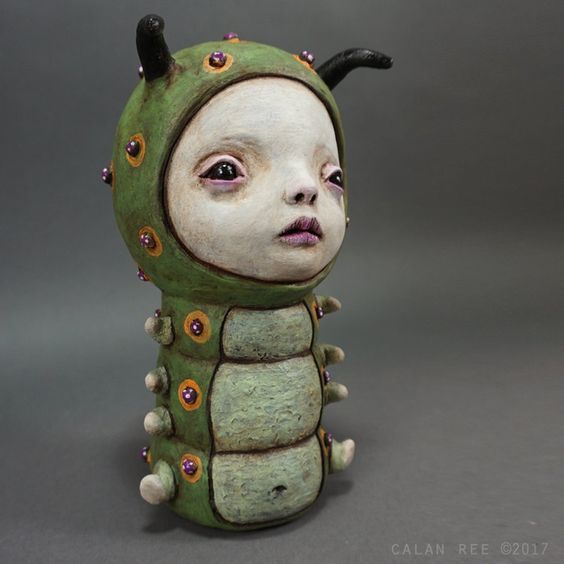 a ceramic sculpture of a green bug with horns and spikes on it's head