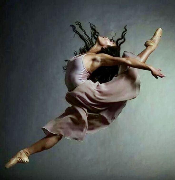 a woman with dreadlocks is in the air above her head and arms as she dances