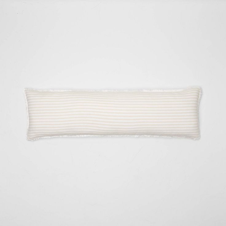 a white and beige striped pillow on a white wall